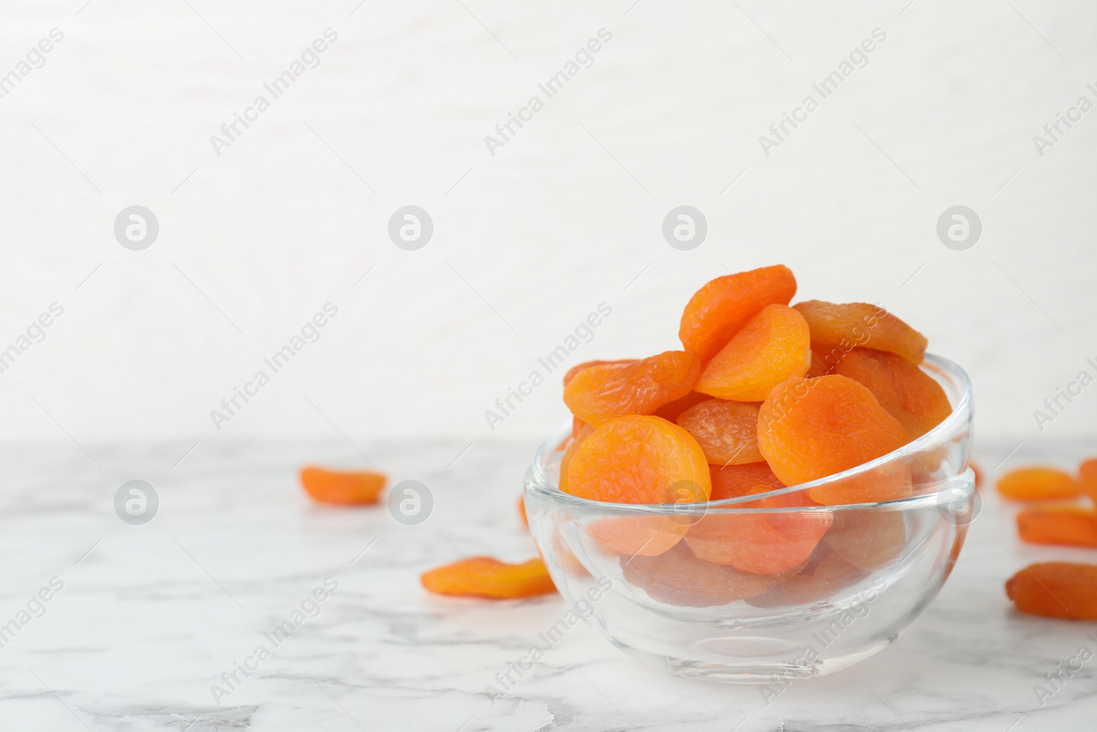 Photo of Bowl with apricots on marble table, space for text. Dried fruit as healthy food