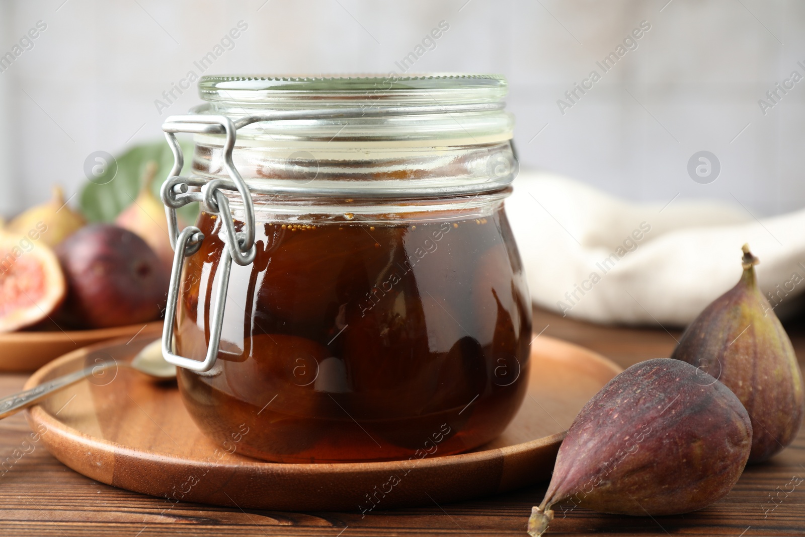 Photo of Jar of tasty sweet fig jam on wooden table