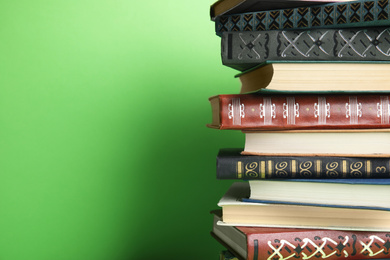 Photo of Stack of hardcover books on green background. Space for text
