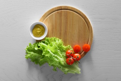 Food photography. Fresh cherry tomatoes, mustard and lettuce on white wooden table, top view
