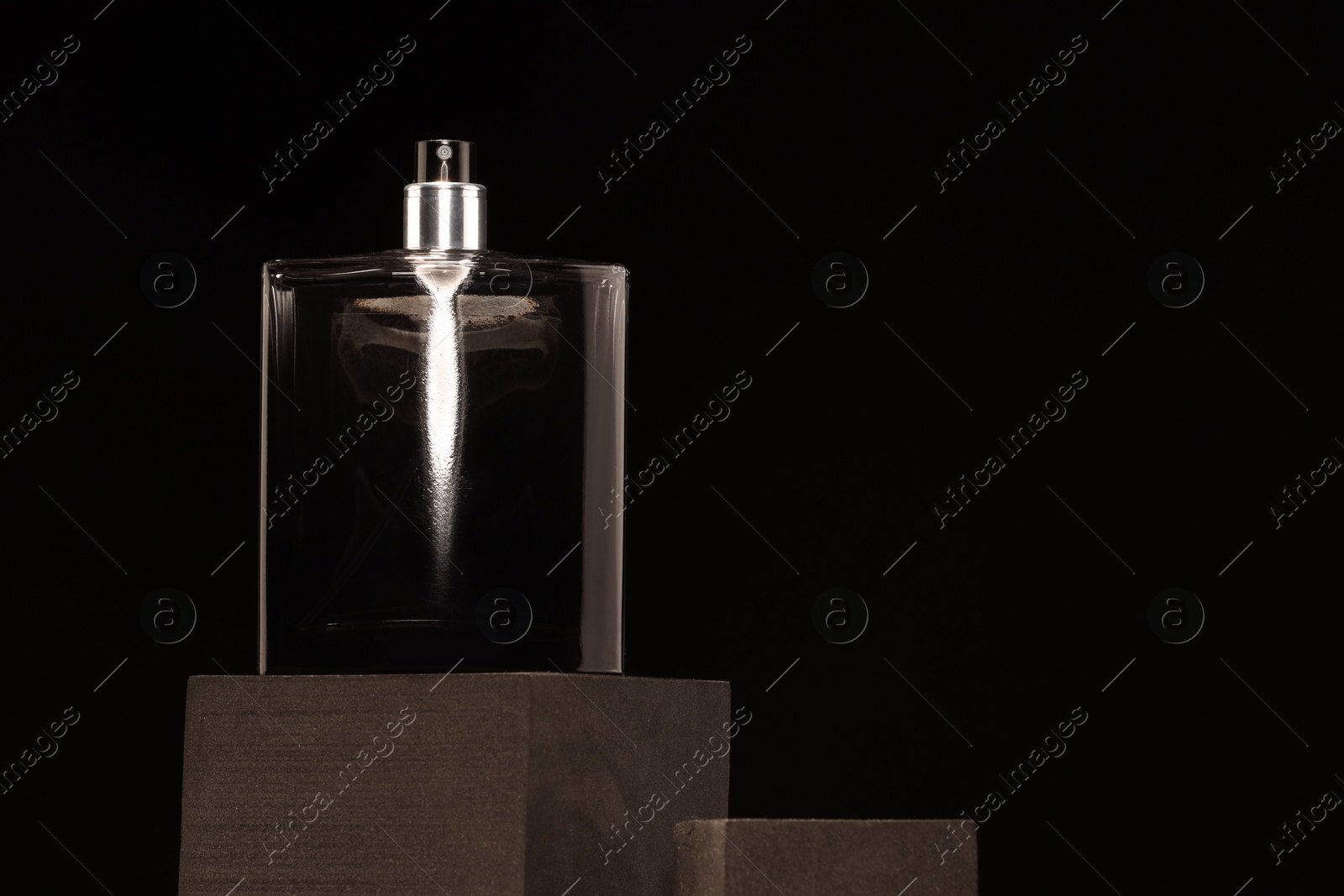 Photo of Luxury men`s perfume in bottle against black background, space for text