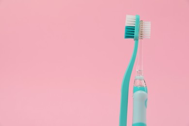 Photo of Electric and plastic toothbrushes on pink background, space for text