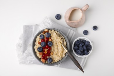 Bowl of delicious cooked quinoa with almonds, cranberries and blueberries on white background, flat lay