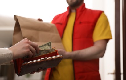Photo of Deliveryman receiving tips from woman indoors, closeup
