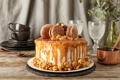 Delicious homemade cake with caramel sauce and popcorn on table