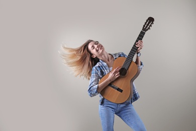 Photo of Young woman playing acoustic guitar on grey background. Space for text