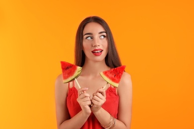 Beautiful young woman posing with watermelon on color background