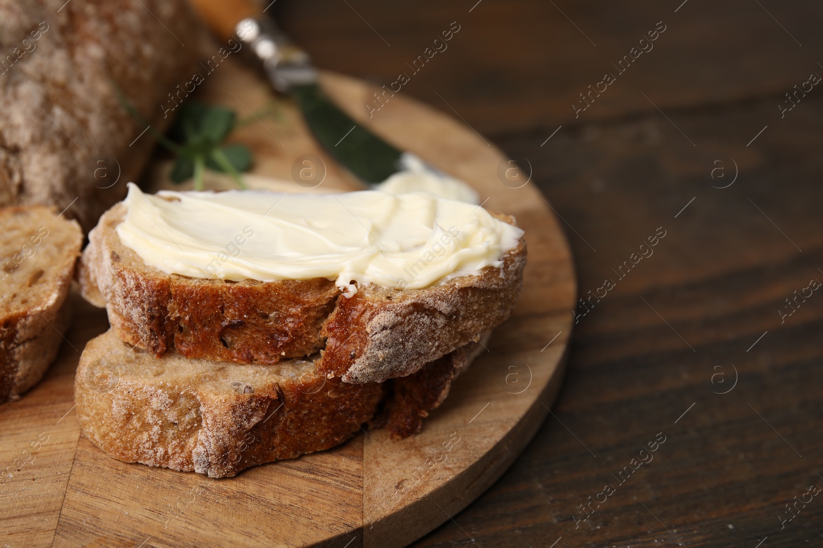 Photo of Slices of tasty bread with butter on wooden table, closeup, Space for text
