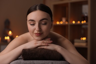 Spa therapy. Beautiful young woman lying on massage table in salon, space for text