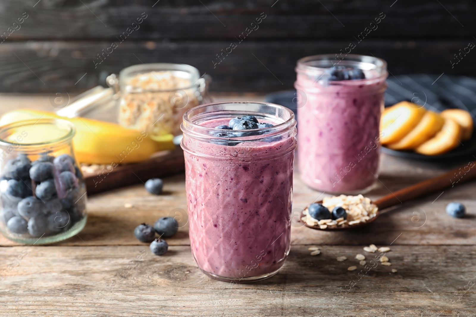 Photo of Jars with blueberry smoothies on wooden table