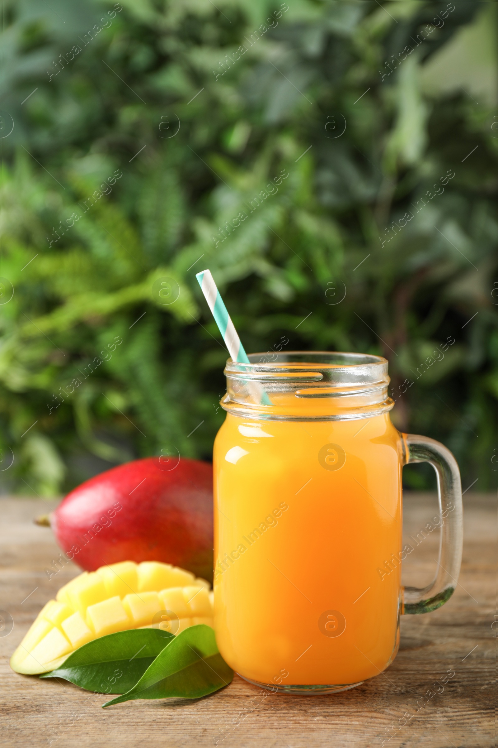 Photo of Mason jar of delicious mango drink on wooden table