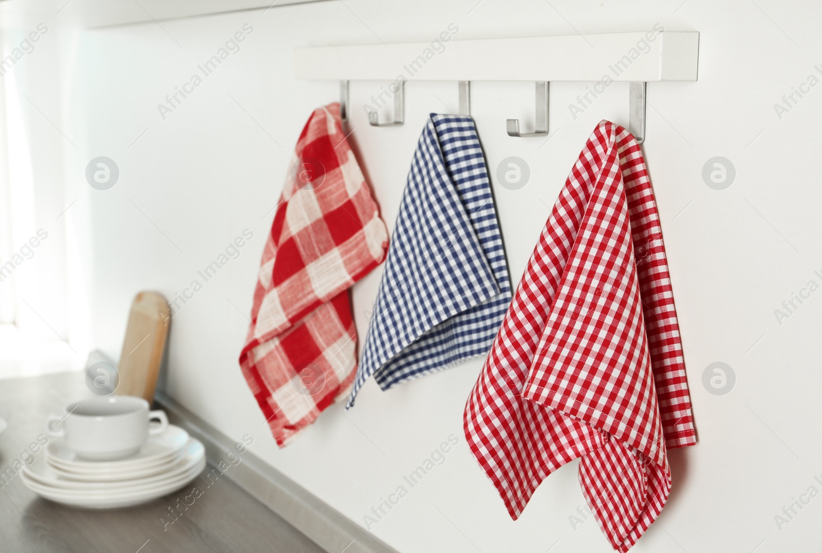 Photo of Different kitchen towels hanging on hook rack indoors