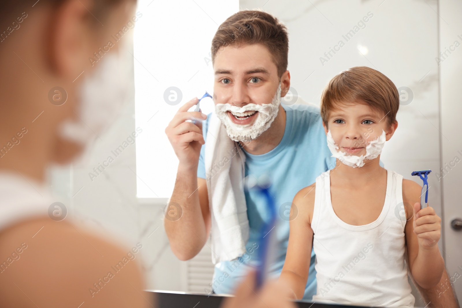 Photo of Dad shaving and son imitating him in bathroom