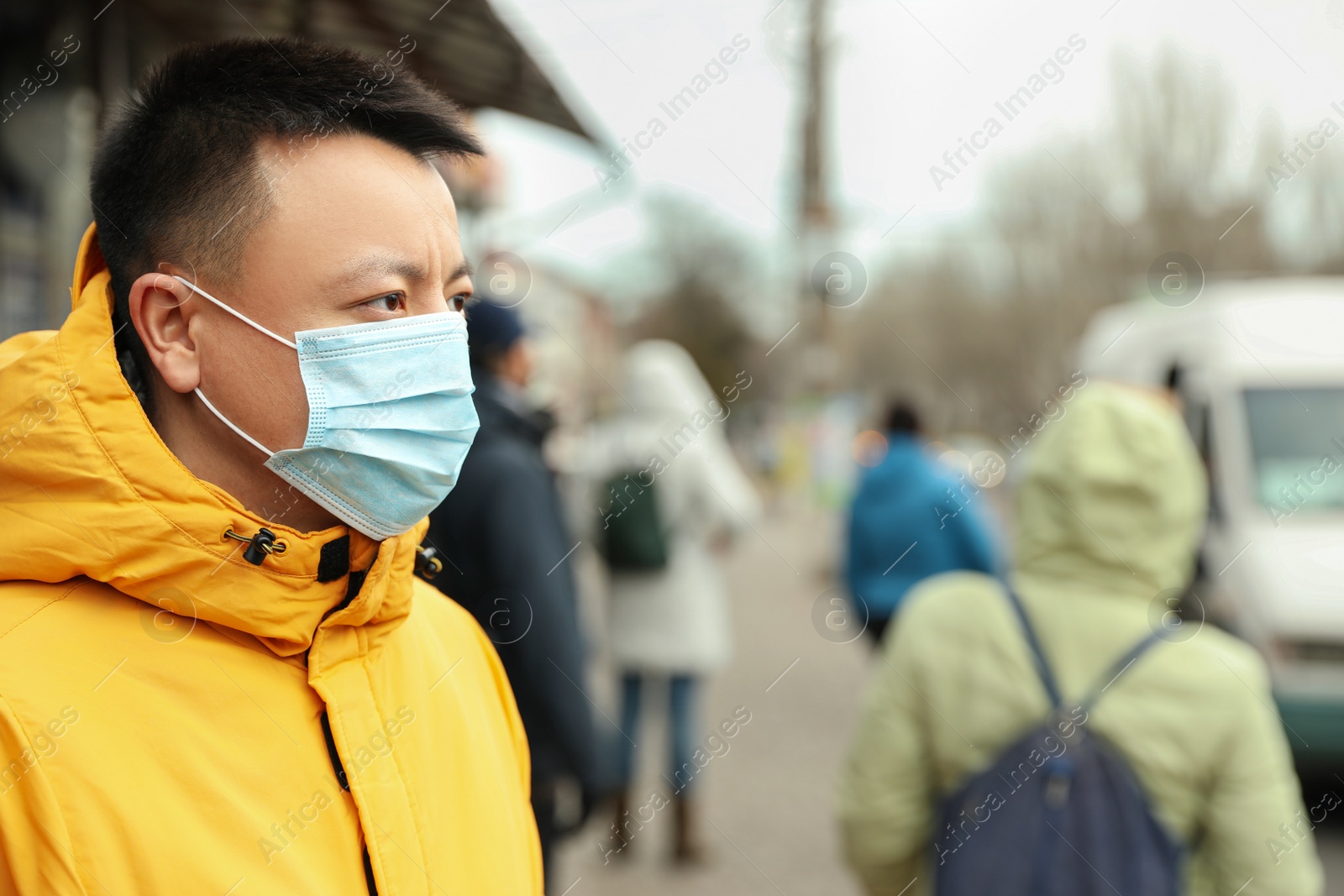 Photo of Asian man wearing medical mask on city street, space for text. Virus outbreak