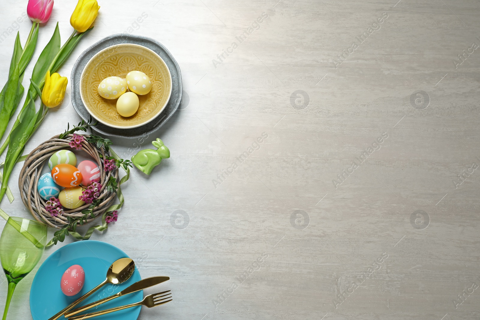 Photo of Festive Easter table setting with painted eggs on wooden background, top view. Space for text