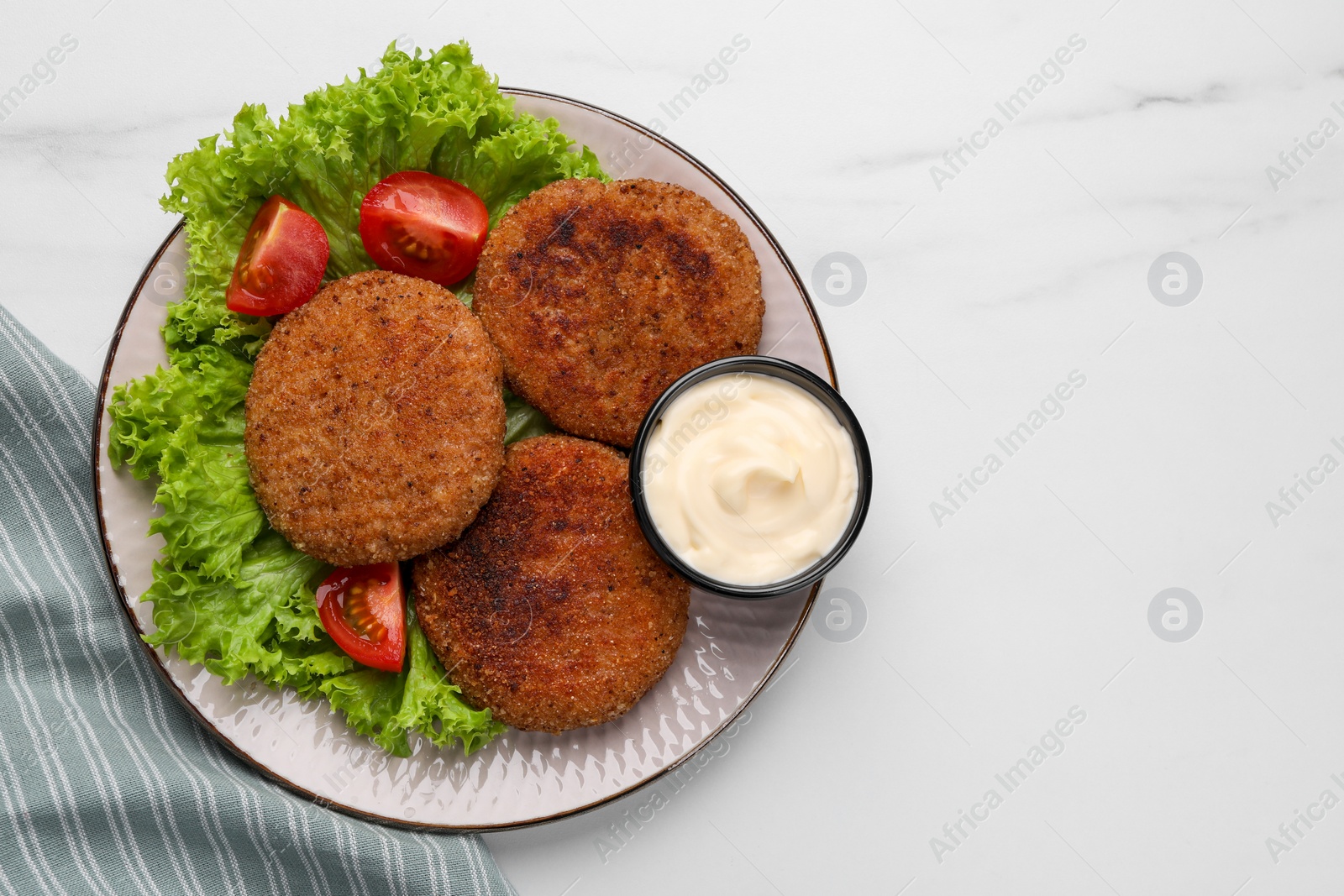 Photo of Plate with delicious vegan cutlets, lettuce, tomatoes and sauce on white marble table, top view. Space for text