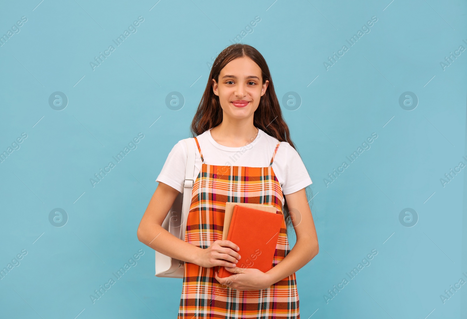 Photo of Teenage student with backpack and books on light blue background