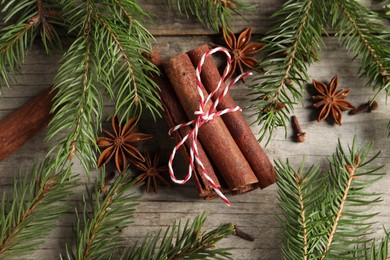 Different spices and fir branches on wooden table, flat lay