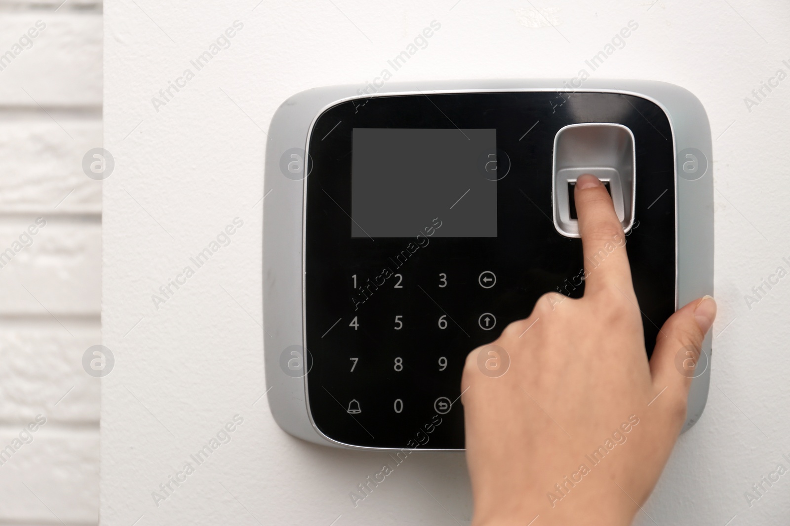 Photo of Woman scanning fingerprint on alarm system indoors, closeup