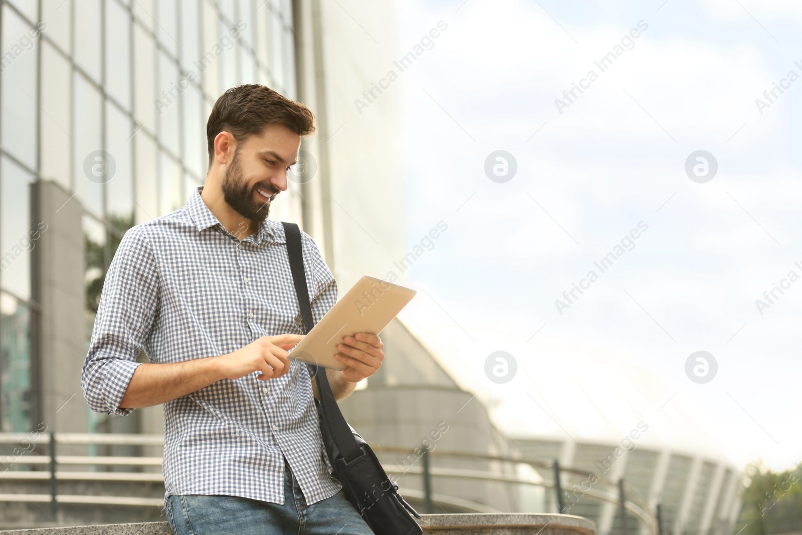 Photo of Handsome man working with tablet on city street