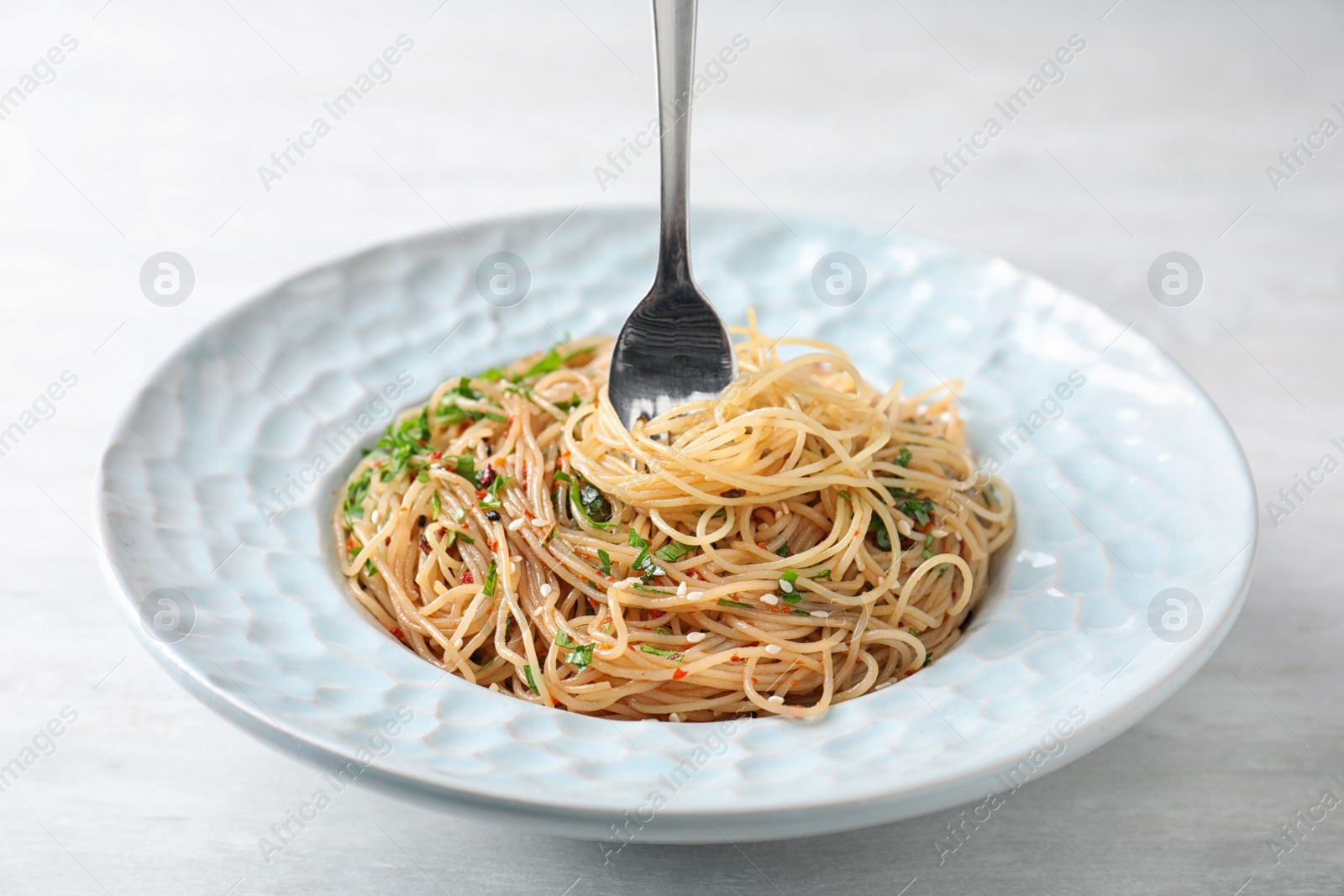 Photo of Plate with tasty cooked noodles and fork on table