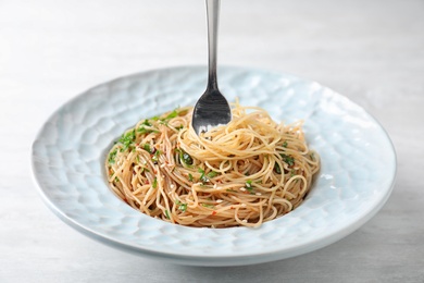 Plate with tasty cooked noodles and fork on table