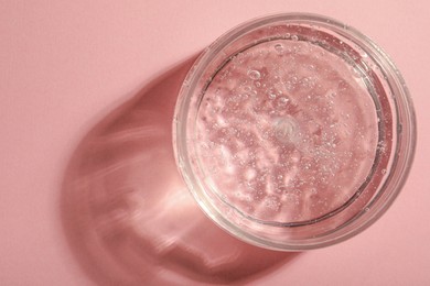 Jar of cosmetic gel on pink background, top view. Space for text