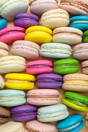Photo of Delicious colorful macarons on beige background, flat lay
