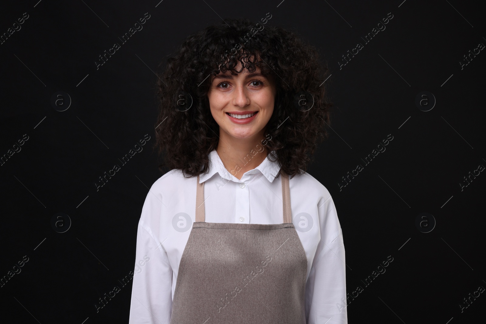 Photo of Happy woman wearing kitchen apron on black background. Mockup for design