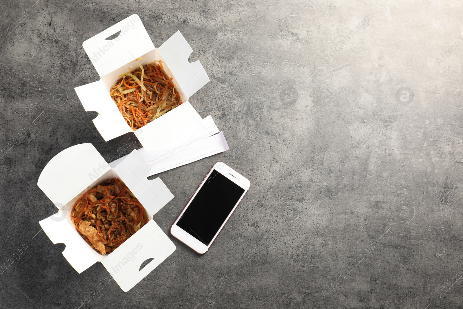 Photo of Smartphone with space for text and Chinese noodles on grey table, top view. Food delivery