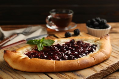Photo of Delicious sweet cottage cheese pastry with cherry jam on wooden table, closeup