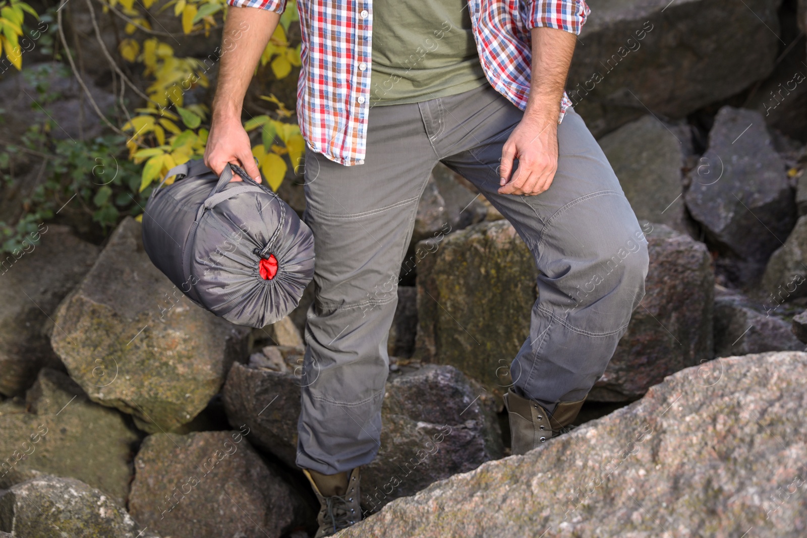 Photo of Male camper with sleeping bag climbing on mountain, closeup