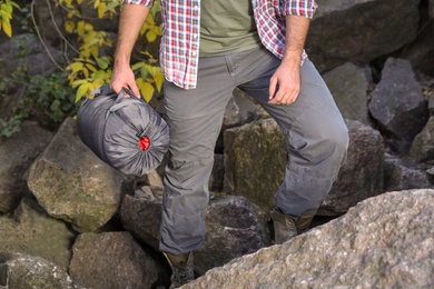 Male camper with sleeping bag climbing on mountain, closeup