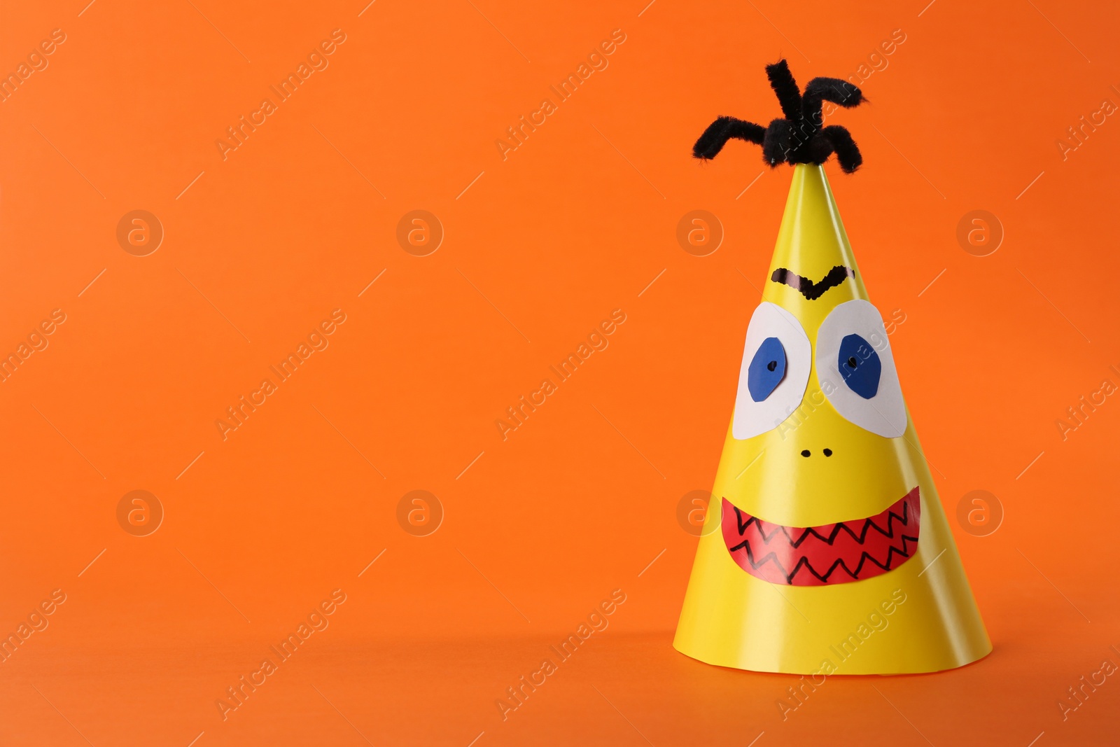 Photo of Funny yellow monster on orange background, space for text. Halloween decoration