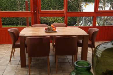 Photo of Wooden table with fruits and stylish chairs on terrace