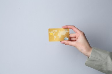 Woman holding credit card on light grey background, closeup