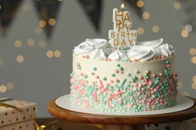 Photo of Beautiful birthday cake with burning candle on wooden stand. Space for text