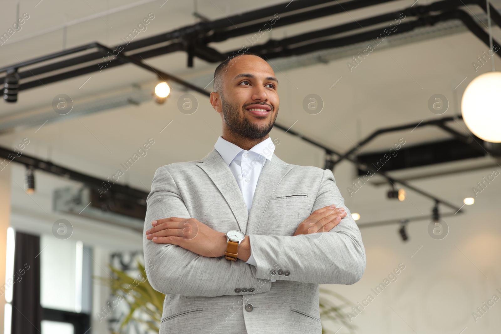Photo of Happy man with crossed arms in office, low angle view. Lawyer, businessman, accountant or manager