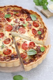 Delicious homemade quiche with prosciutto on light grey table