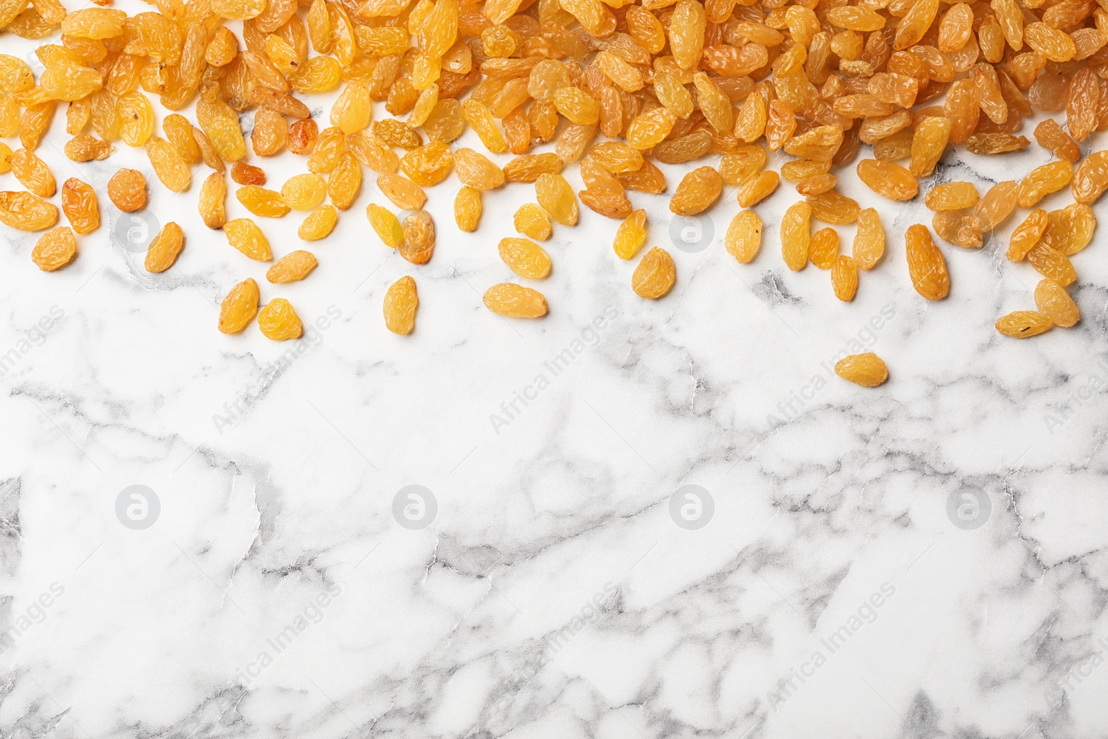 Photo of Many raisins and space for text on marble background, top view. Dried fruit as healthy snack