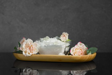 Photo of Glass bowl with natural sea salt and beautiful flowers on mirror surface