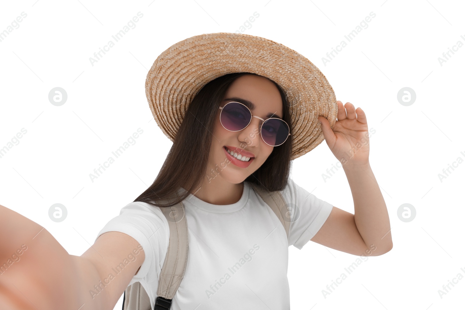 Photo of Smiling young woman in sunglasses and straw hat taking selfie on white background