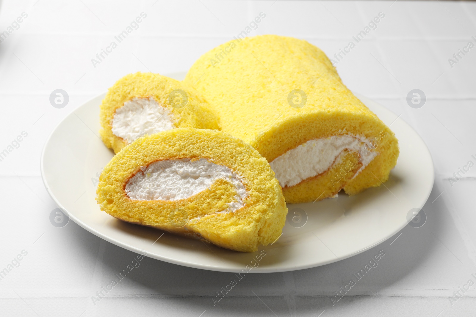 Photo of Delicious cake roll on white tiled table, closeup