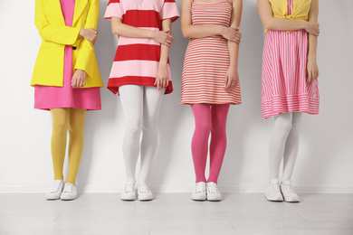 Women wearing colorful tights near white wall, closeup