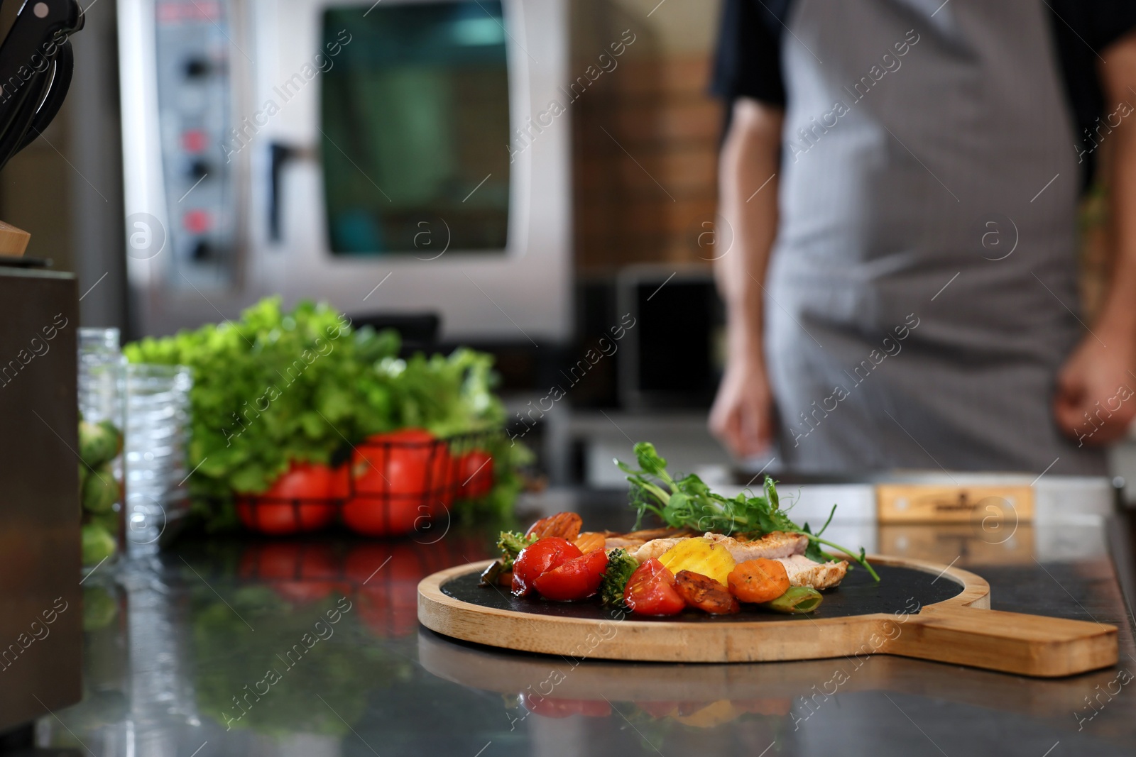 Photo of Professional chef in restaurant kitchen, focus on table with delicious grilled meat