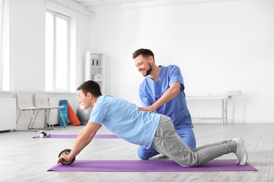 Photo of Physiotherapist working with male patient in clinic