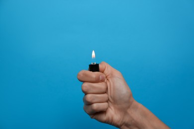 Photo of Woman holding lighter on light blue background, closeup. Space for text