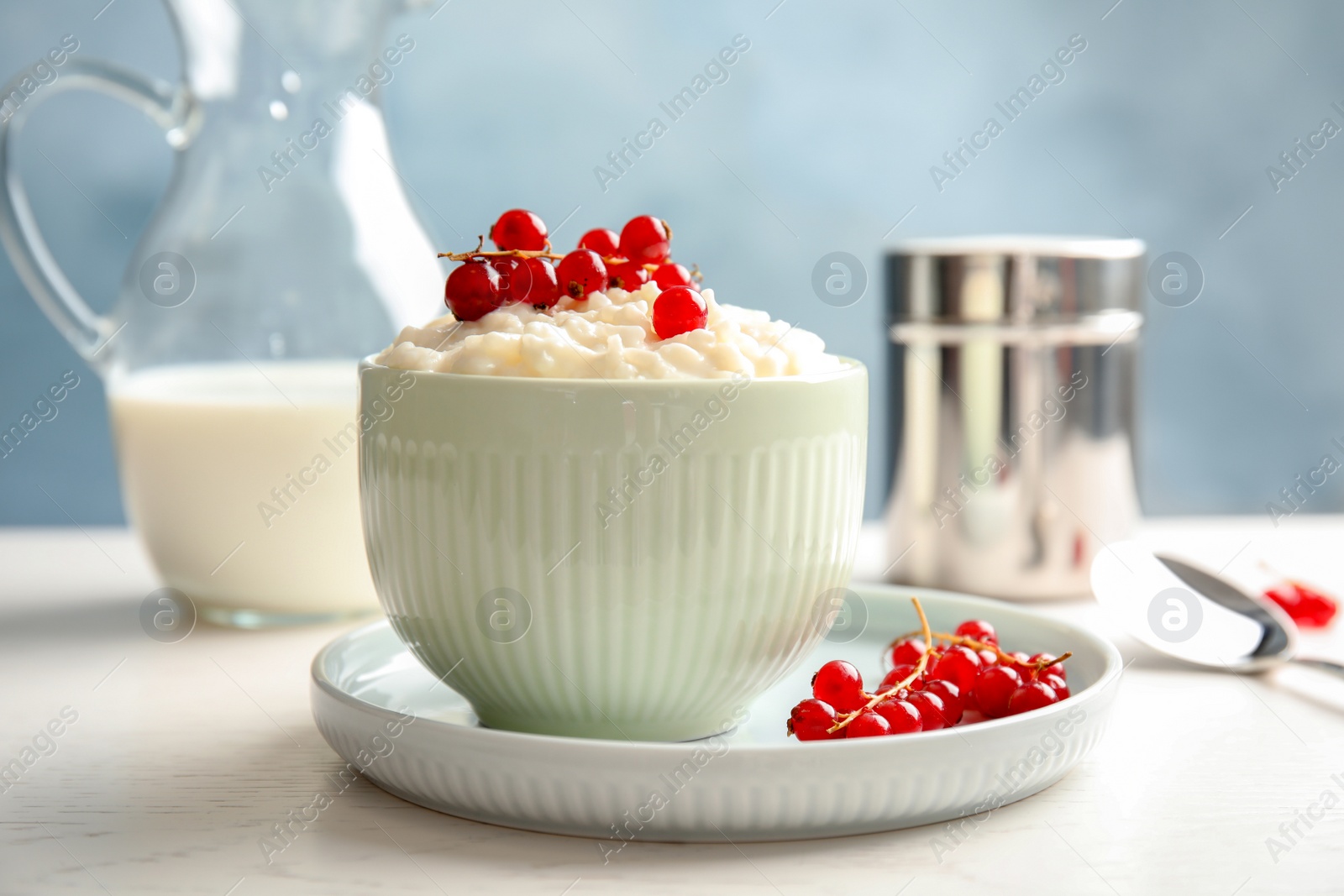 Photo of Creamy rice pudding with red currant in bowl on table