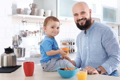 Photo of Dad having breakfast with little son in kitchen