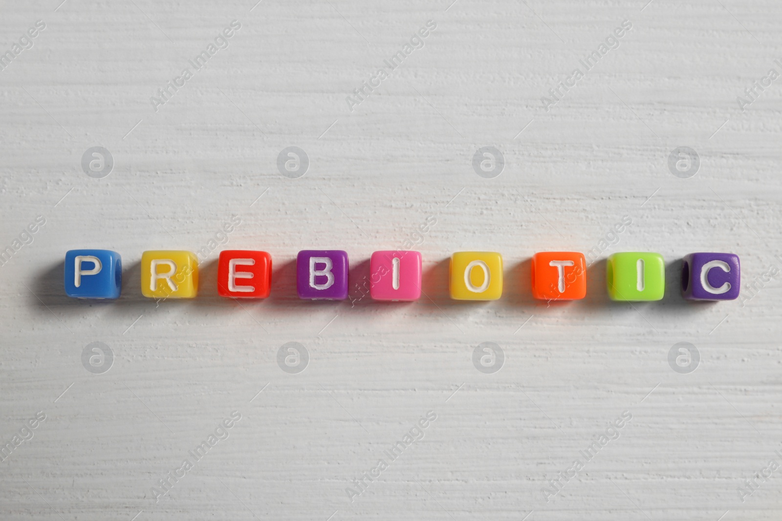 Photo of Word Prebiotic made of colorful cubes on wooden table, flat lay